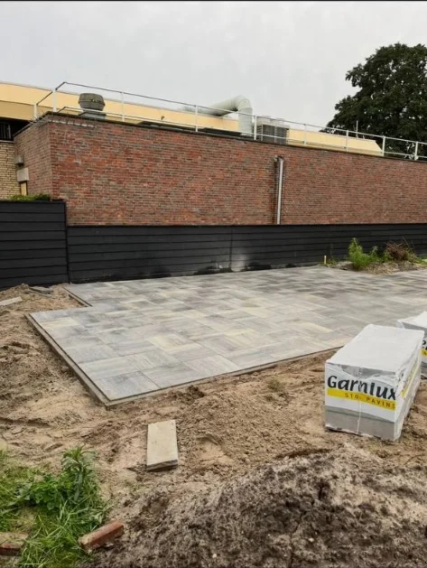 Zandbed en eerste tegels van een terras in aanleg